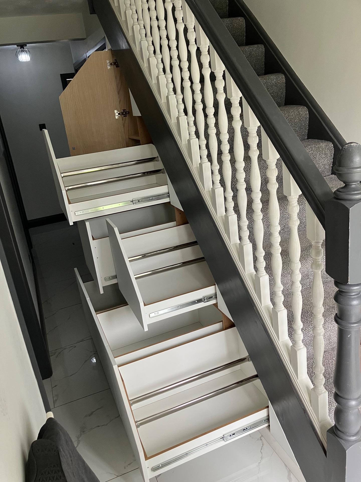 After: Wasted space under the stairs converted into ample storage using drawers and door with shelving